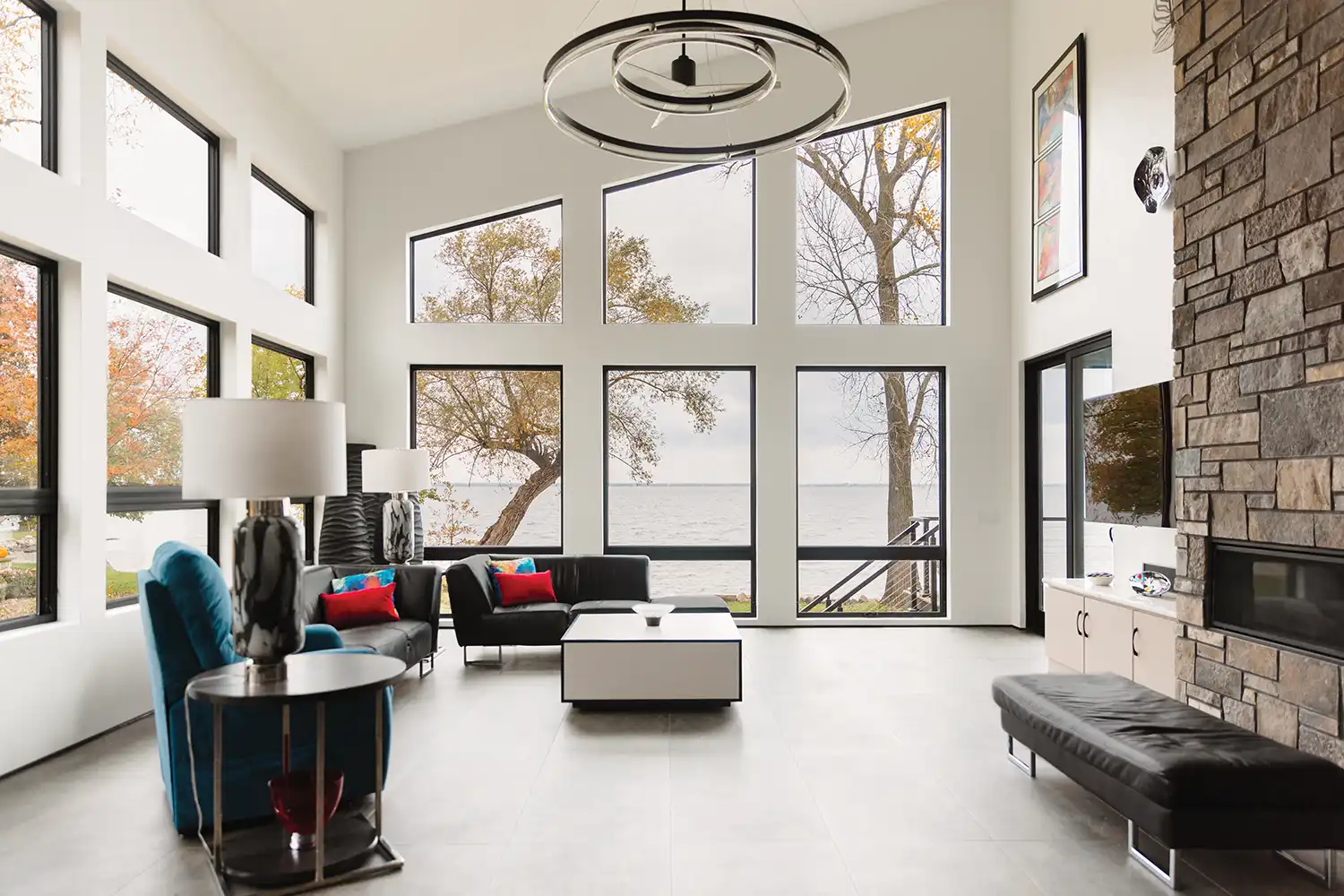 Home interior featuring black Marvin Replacement special shape windows overlooking a lake.