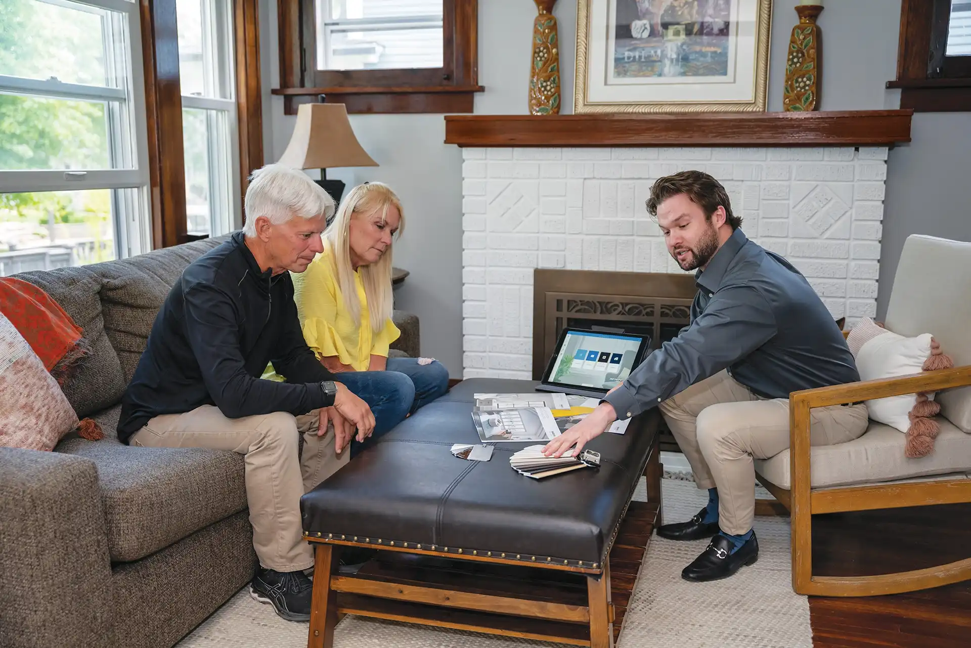 A Marvin Replacement design consultant talks with a middle aged couple about window and patio door design options in a living room.