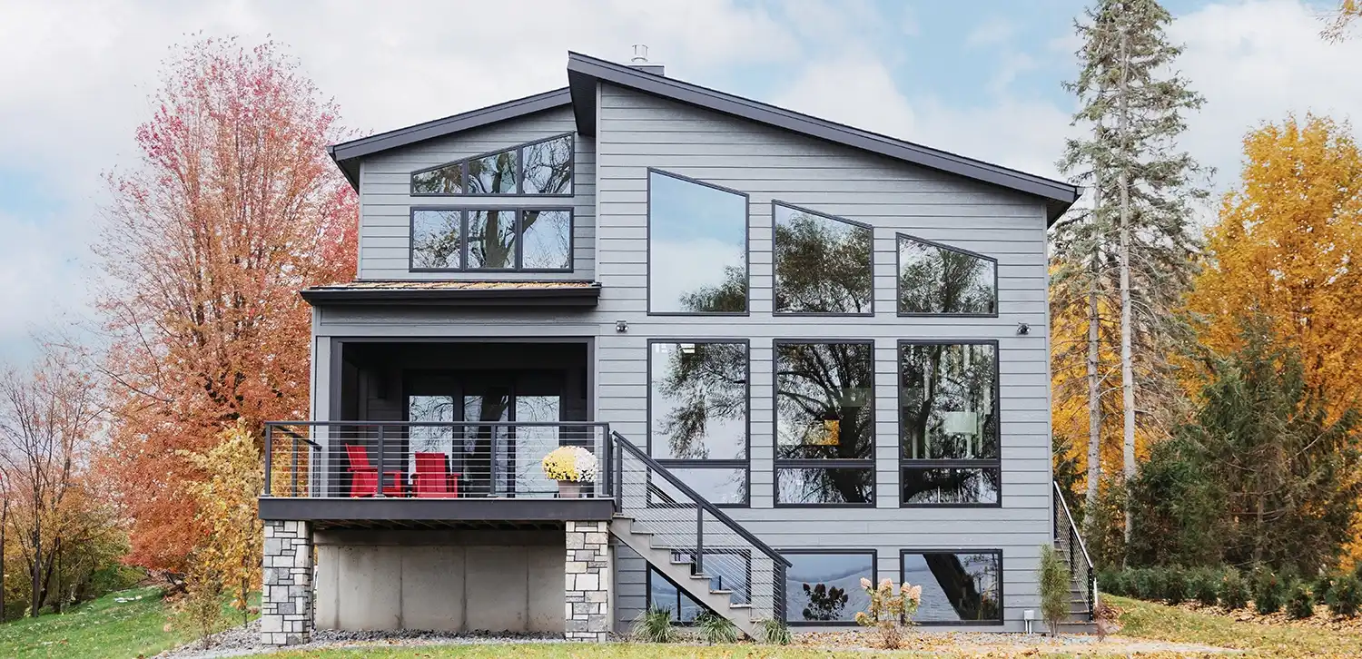 Exterior view of a home with special shape, awning and picture windows in fall.