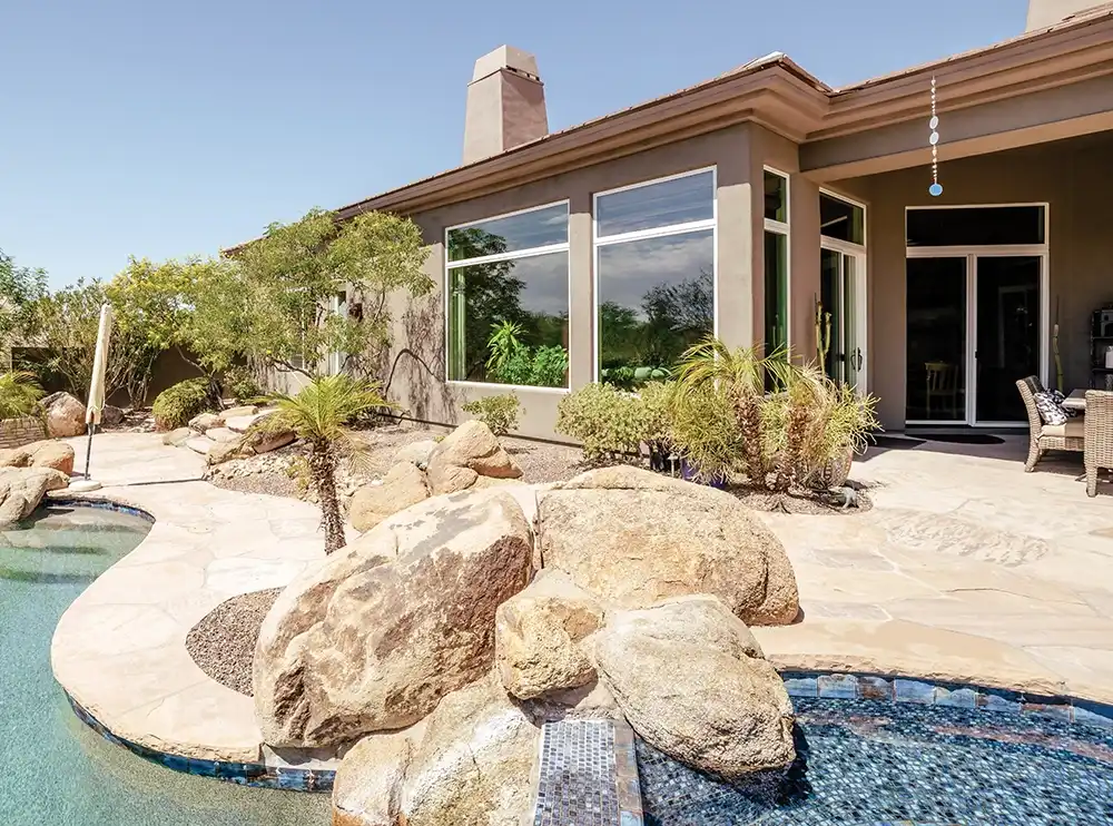 Exterior view of a stucco home in the southwest with white picture windows