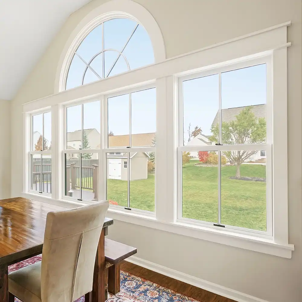 Interior view of a white arch window above double hung windows.